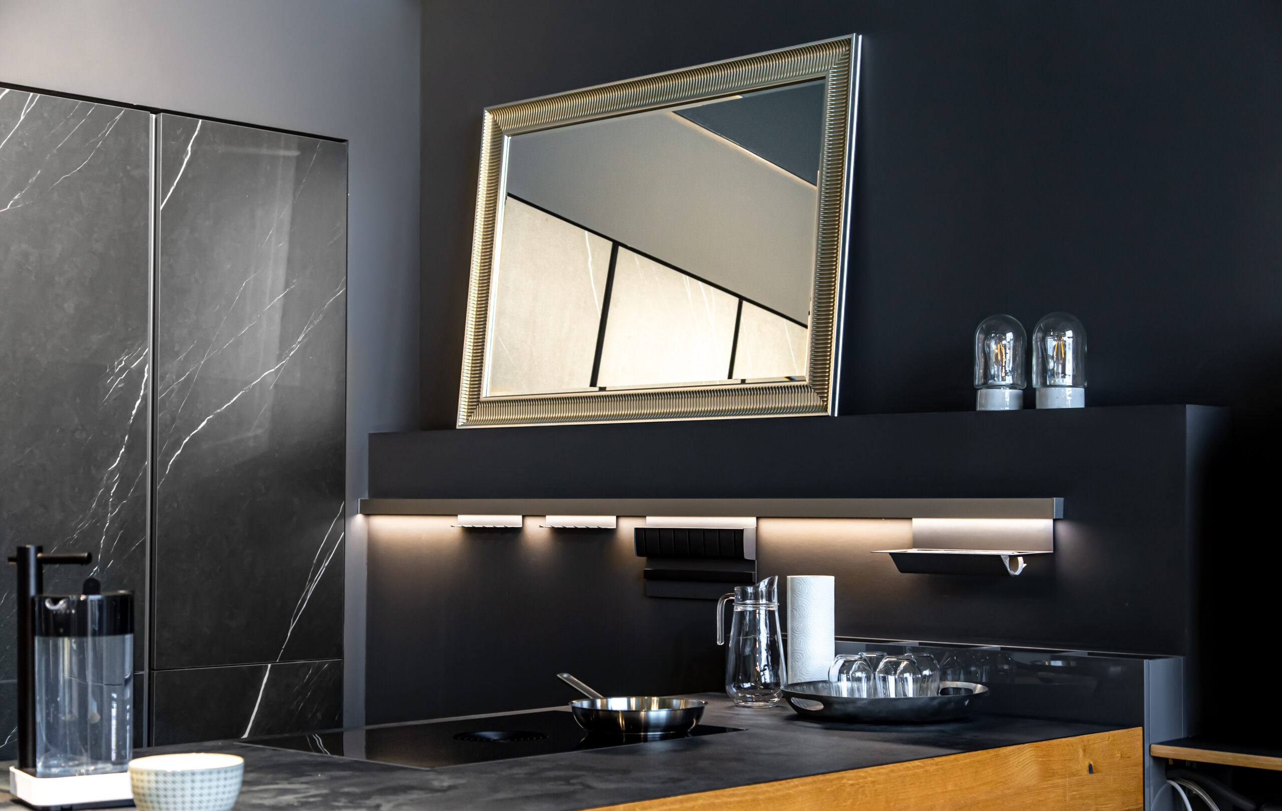 Part of the interior of the kitchen in black, with a mirror, modern minimalism.