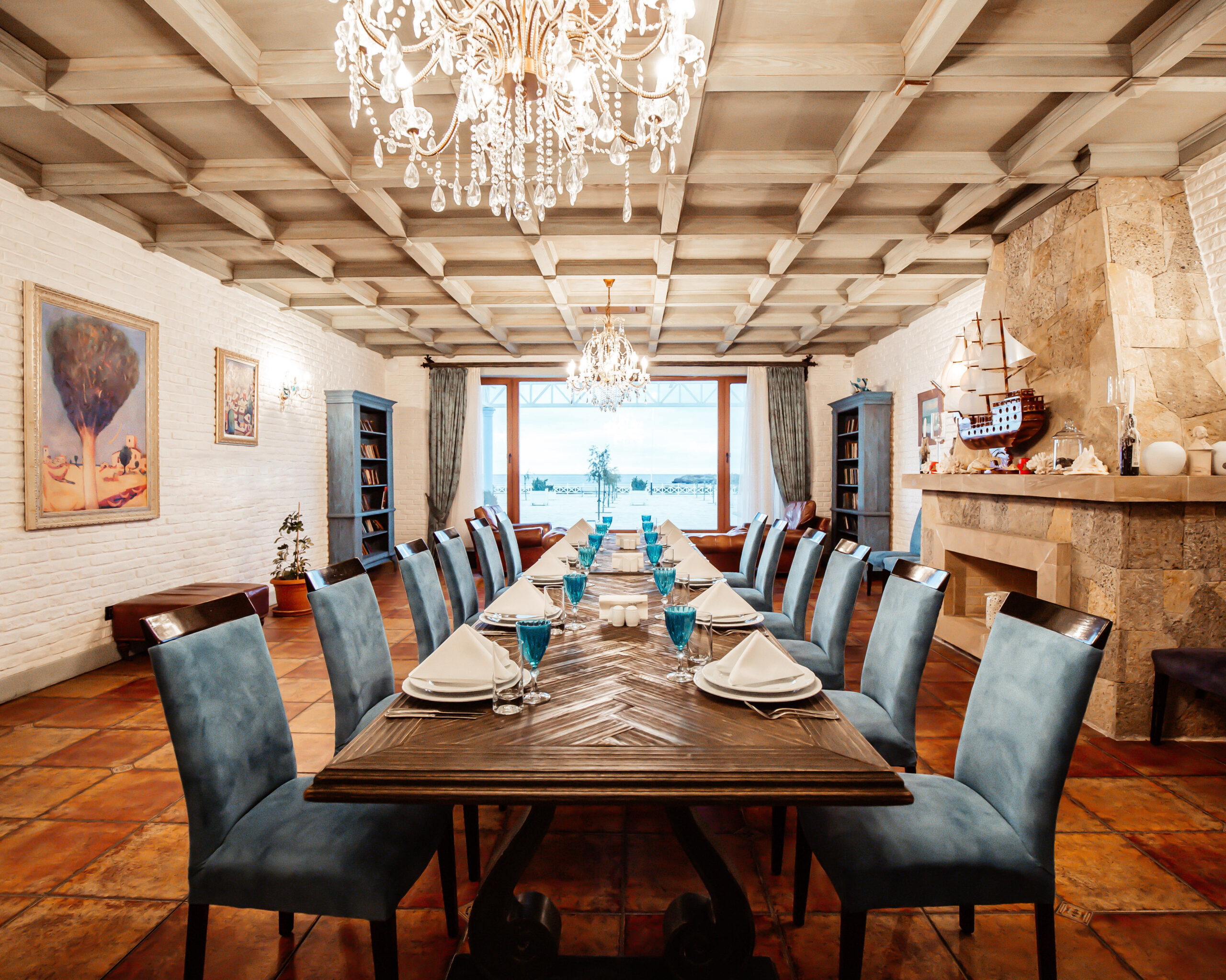 restaurant table for 12 persons with blue chairs fireplace white brick walls wide window
