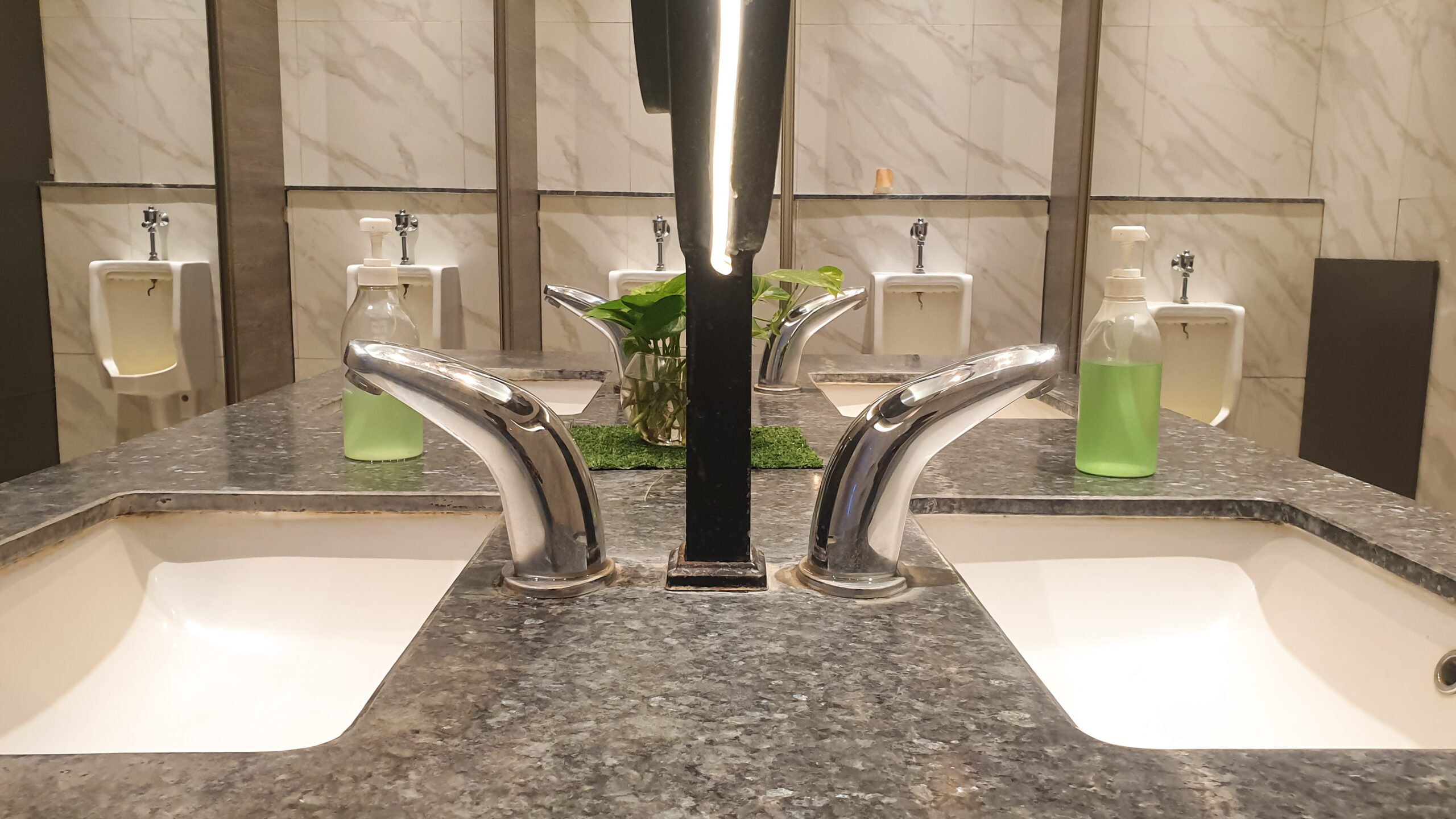 Sinks, urinals and soap dispensers in a well-maintained, modern commercial restroom or bathroom